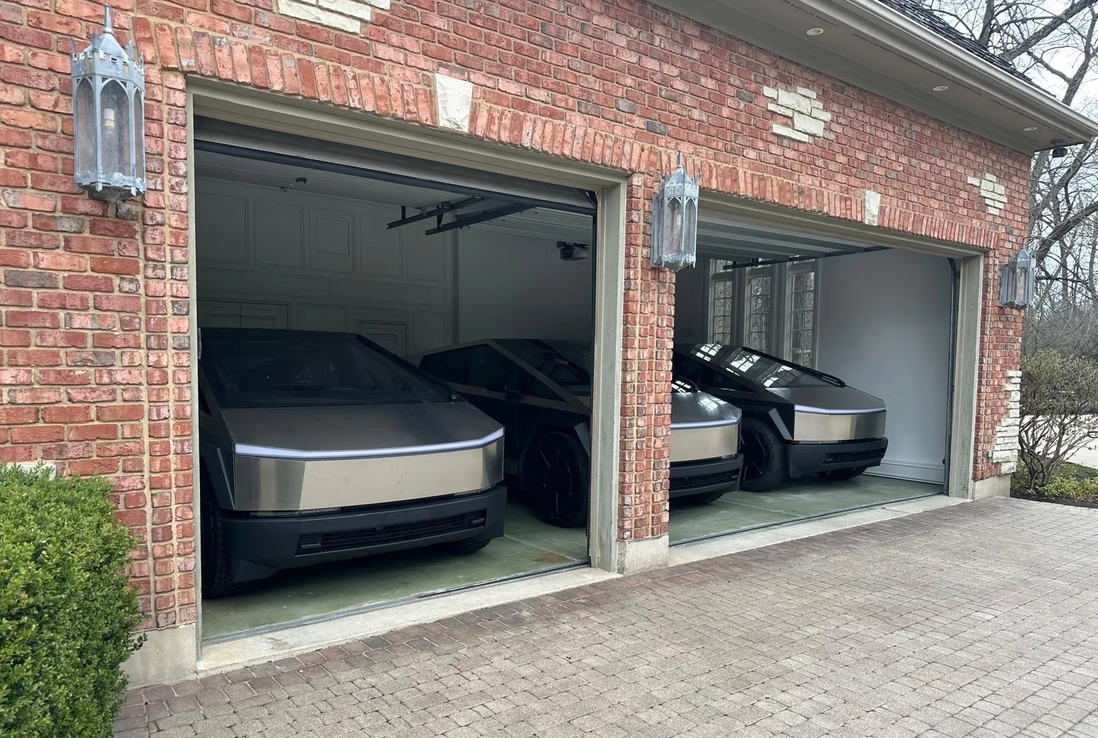 Three stainless-steel Tesla Cybertrucks parked in a garage